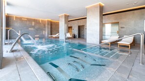 A modern indoor pool with clear water, metal railings, and lounge chairs. - Hotel El Mirador (Loja)