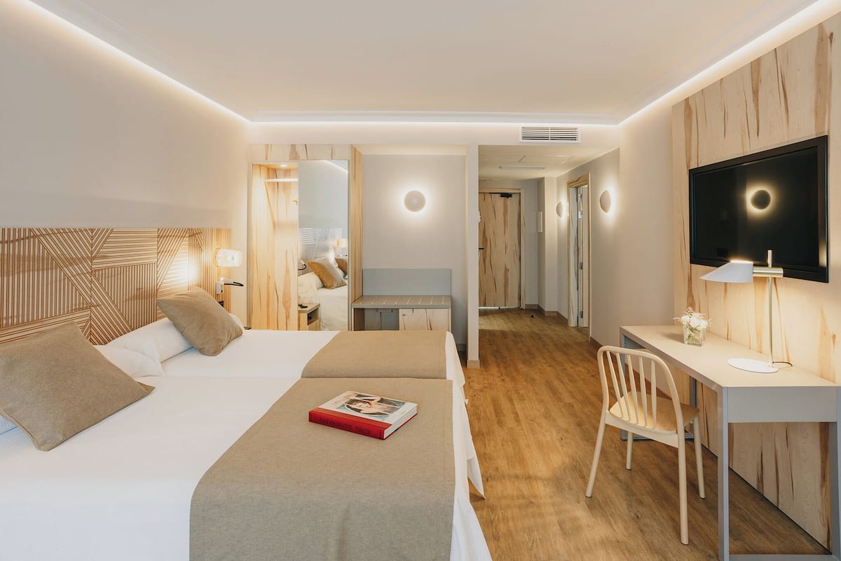 Une chambre d’hôtel moderne équipée d’un lit, d’un bureau, d’une chaise et d’une télévision.