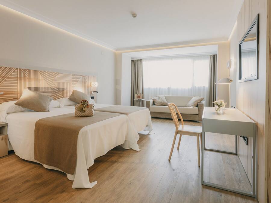 A modern hotel room with a large bed, a desk, and a comfortable seating area.