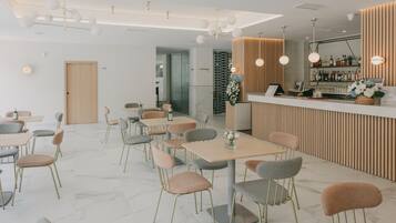 A modern restaurant with a bar area, marble flooring, and a variety of seating options.