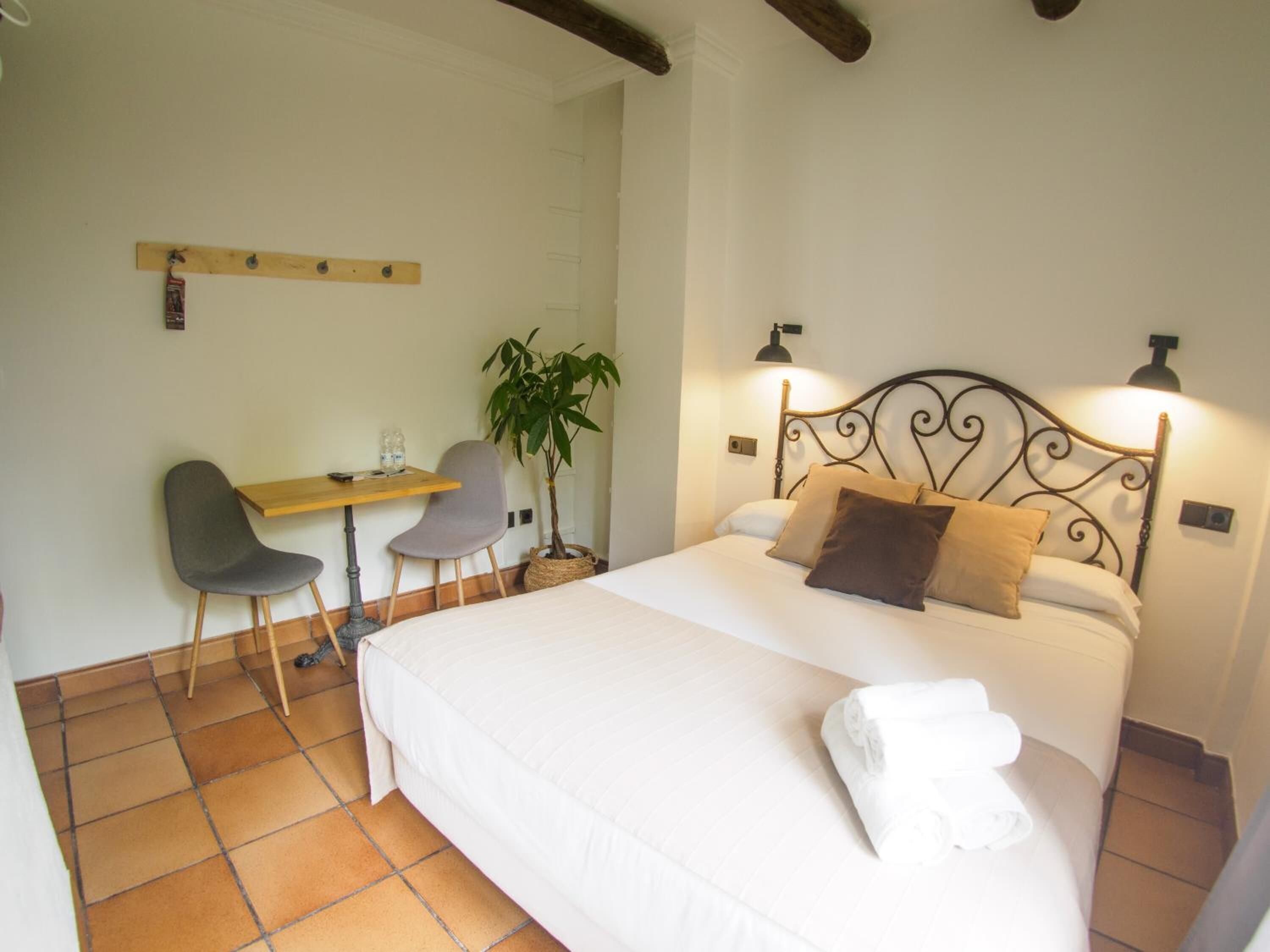Une chambre à coucher avec un lit, deux lampes de chevet, un bureau avec une chaise et une plante en pot.