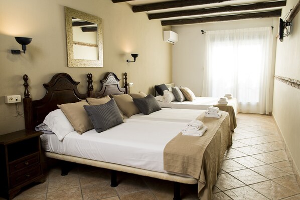 A hotel room with two beds, a nightstand, a mirror, and a window with curtains. - El Balcón de Nieves (La Zubia)
