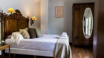 A bedroom with a wooden bed, two bedside lamps, a mirror, and a wall sign.