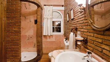 Een badkamer met een grote spiegel, een bad en een douchehoek.