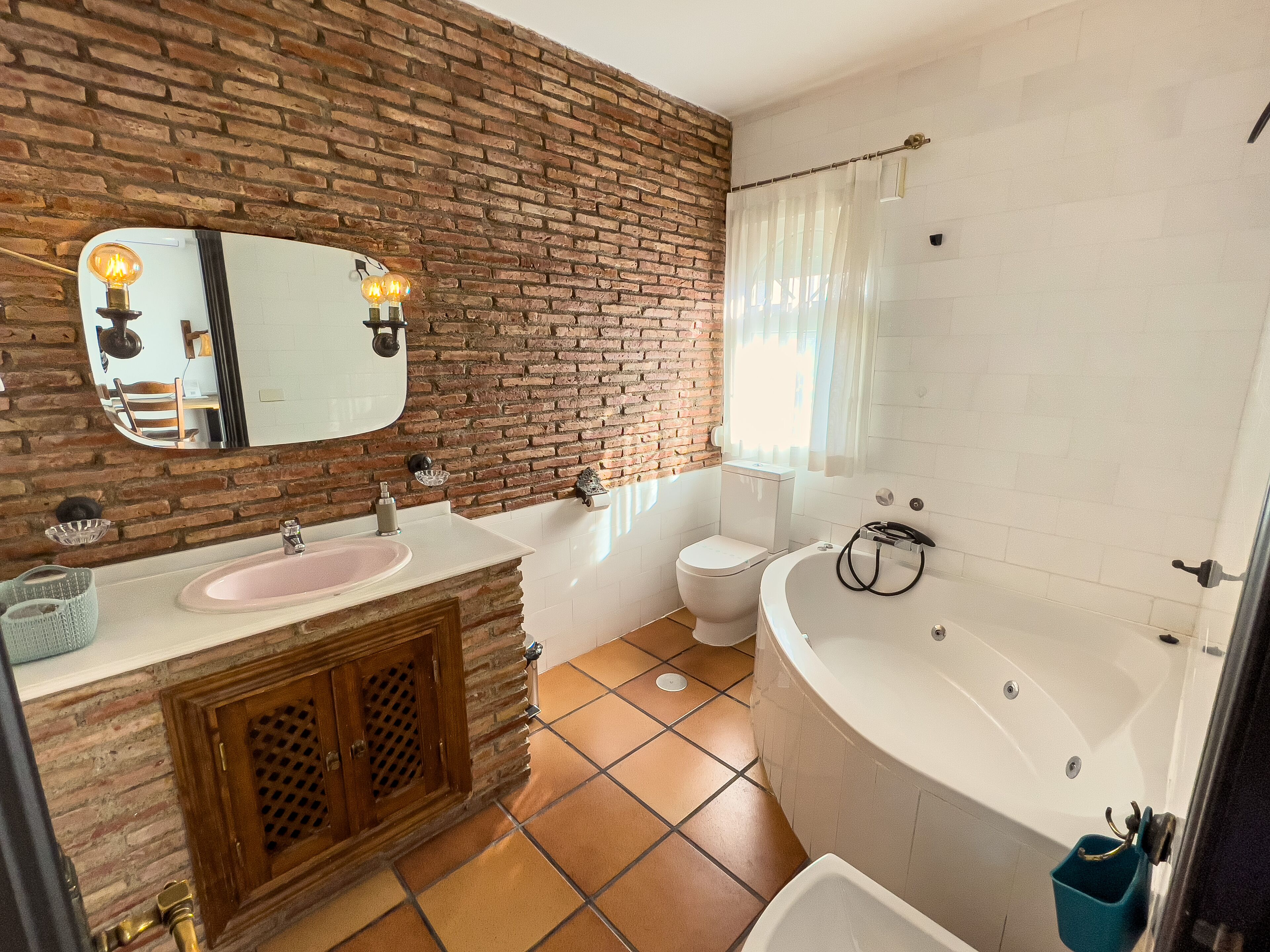 A bathroom with a brick wall, a sink, a toilet, and a bathtub.