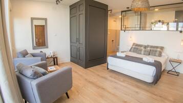 Een moderne slaapkamer met een groot bed, een grijze bank en een garderobe.