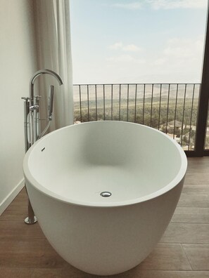 Un baño moderno con una bañera independiente, ducha y vistas a un paisaje montañoso.