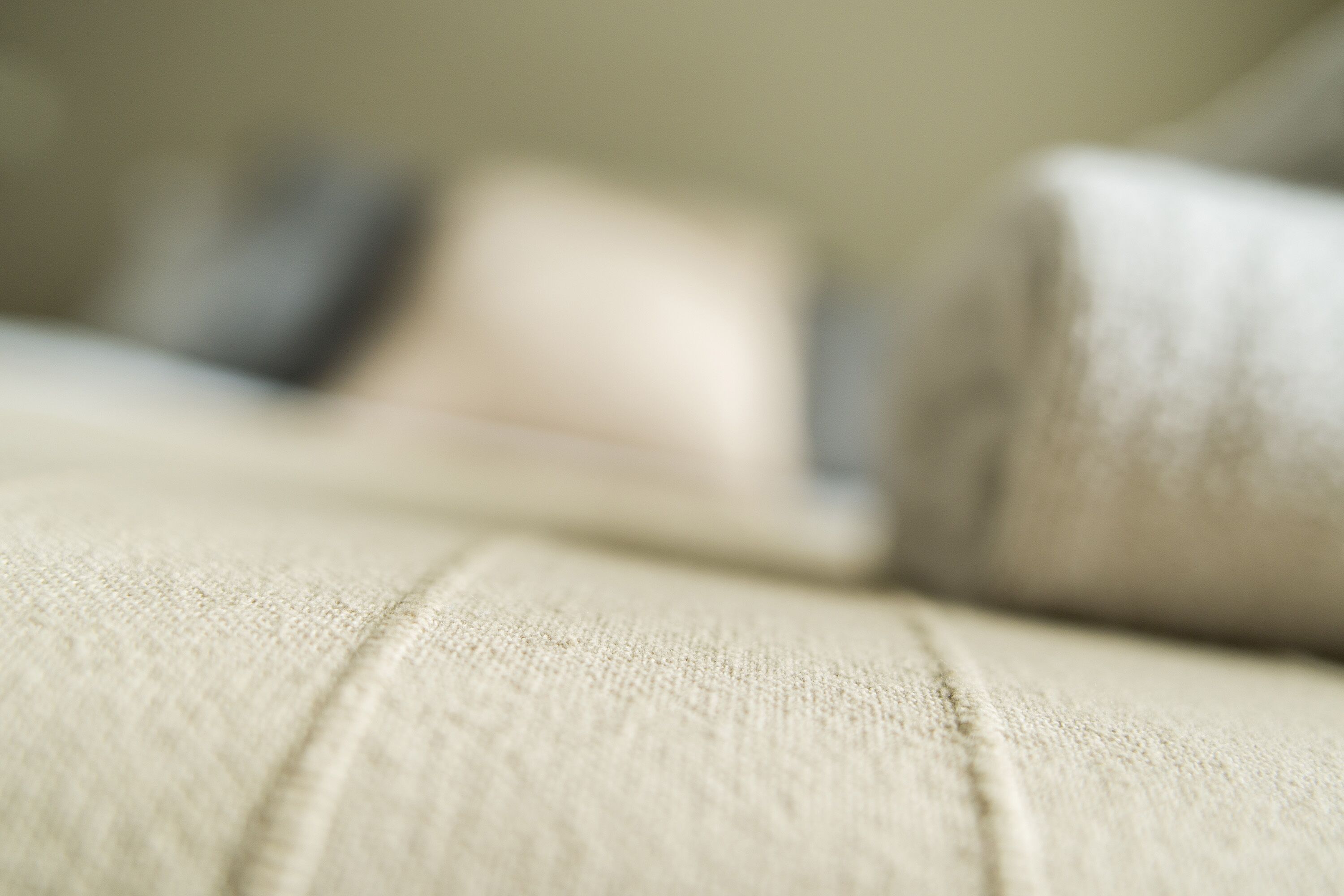 A close-up of a textured fabric, likely a sofa or cushion, with a blurred background.