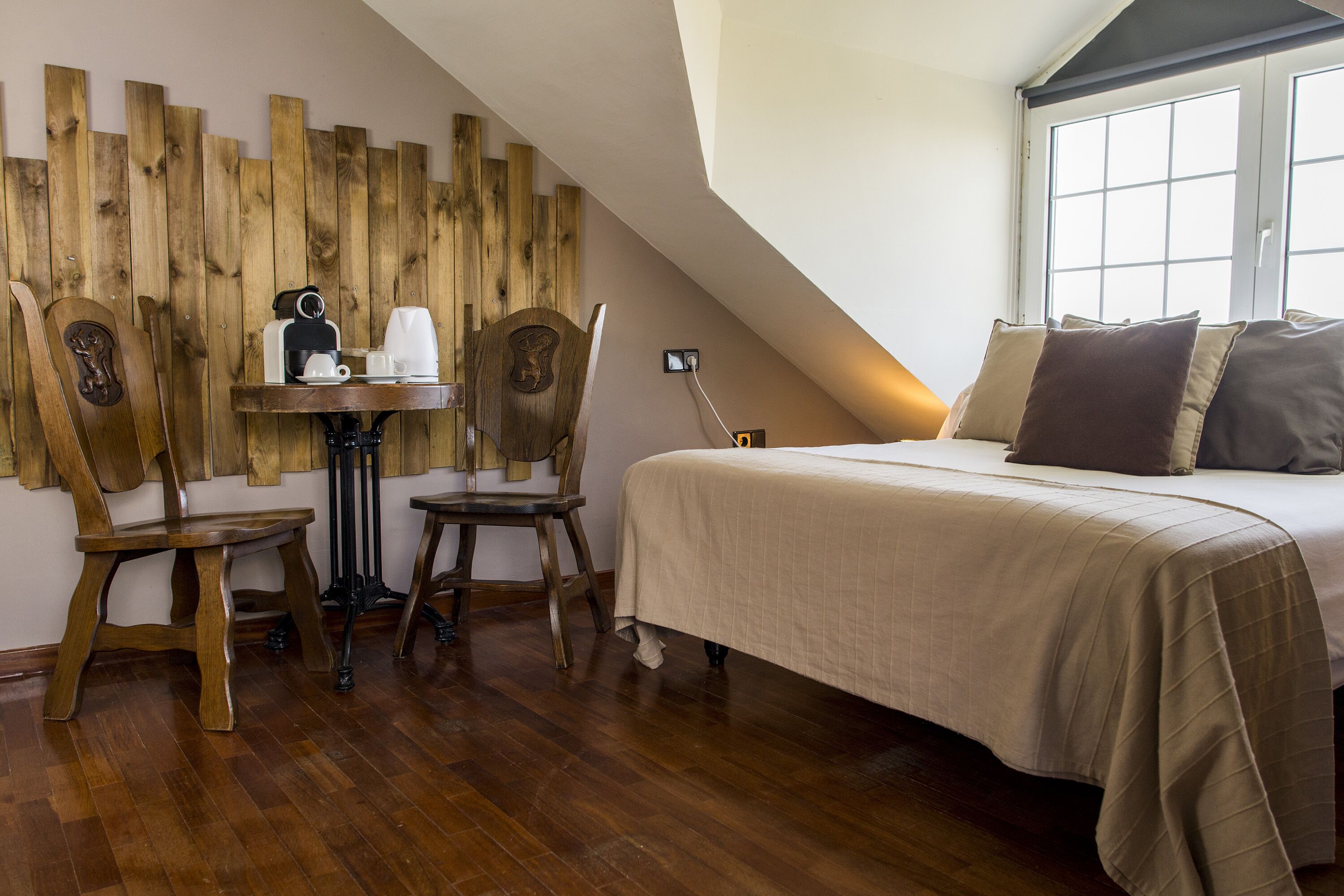 Ein Schlafzimmer mit einem Bett, einer Holzwand, einem Tisch mit Kaffeemaschine und zwei Stühlen.