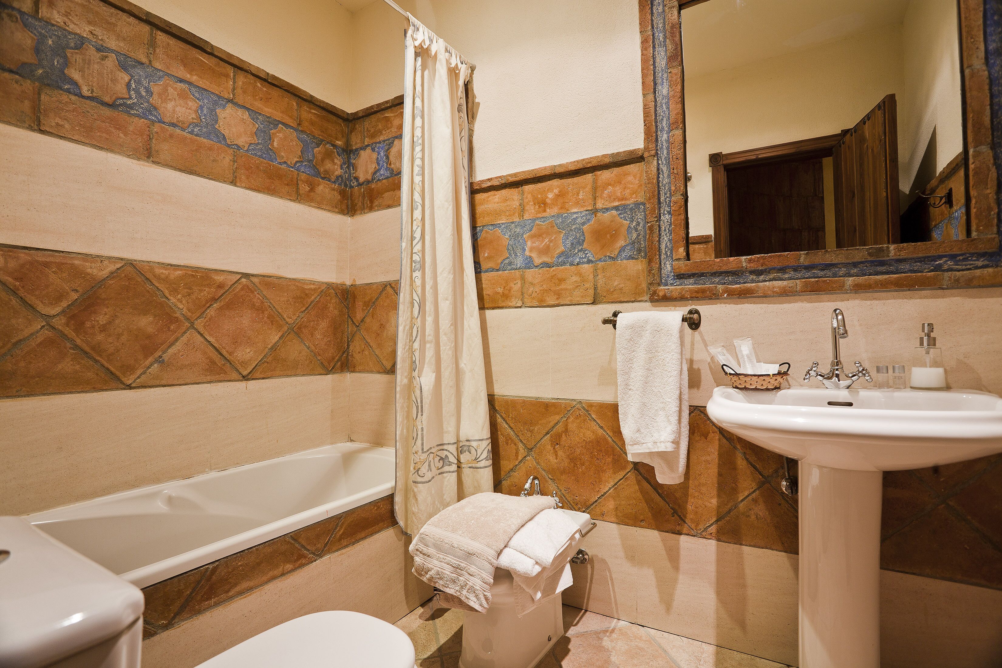 A bathroom with a bathtub, toilet, sink, and a mirror.