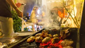 A grill with food being cooked outdoors at night.