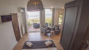 Una habitación de hotel con una cama, dos sillones, una mesita y un balcón con vistas.