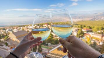 Due mani che sorreggono bicchieri di vino con vista panoramica su una cittadina.