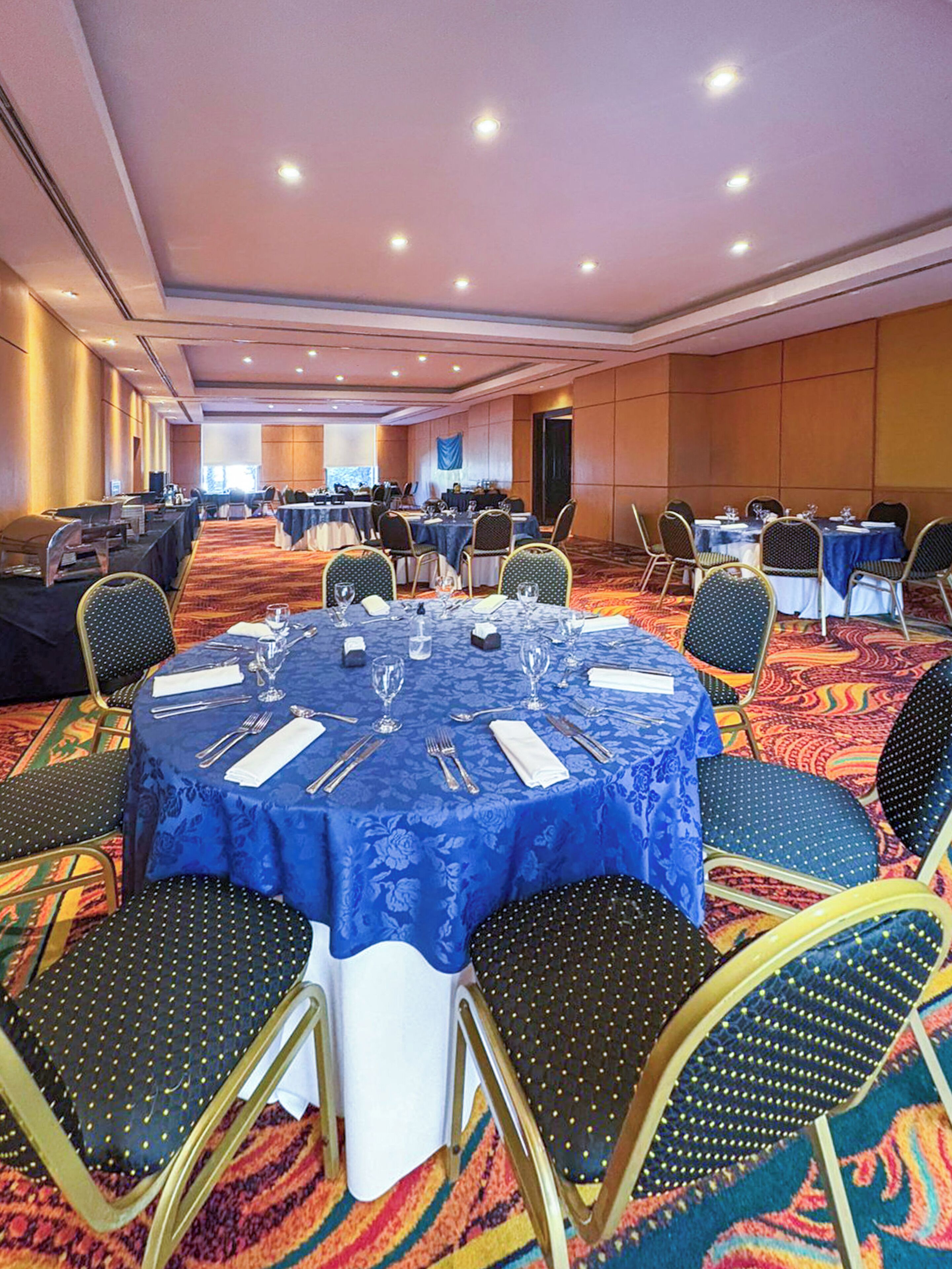 A conference room with round tables, chairs, and a carpeted floor.