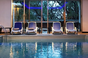A poolside area with four lounge chairs and a glass railing.