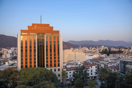 A modern hotel with a prominent sign, surrounded by urban buildings and mountains in the background.. Hotel Alejandro I, Affiliated by Meliá