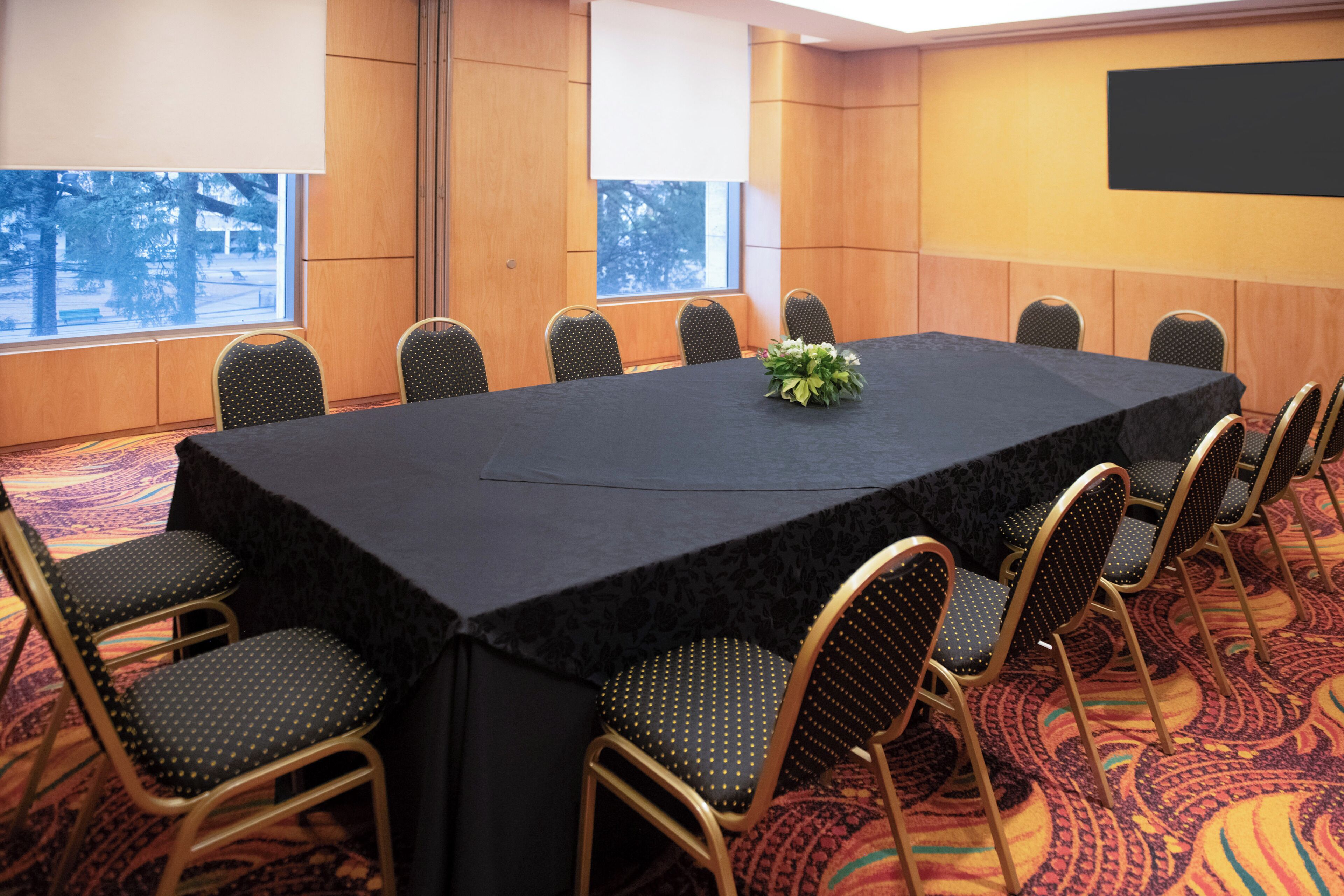 Une salle de conférence avec une longue table, des chaises et un sol recouvert de moquette.