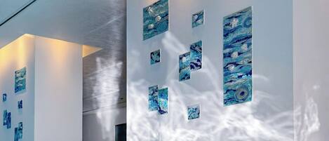 Una piscina interior moderna con agua azul cristalina, paredes blancas y obras de arte azules.