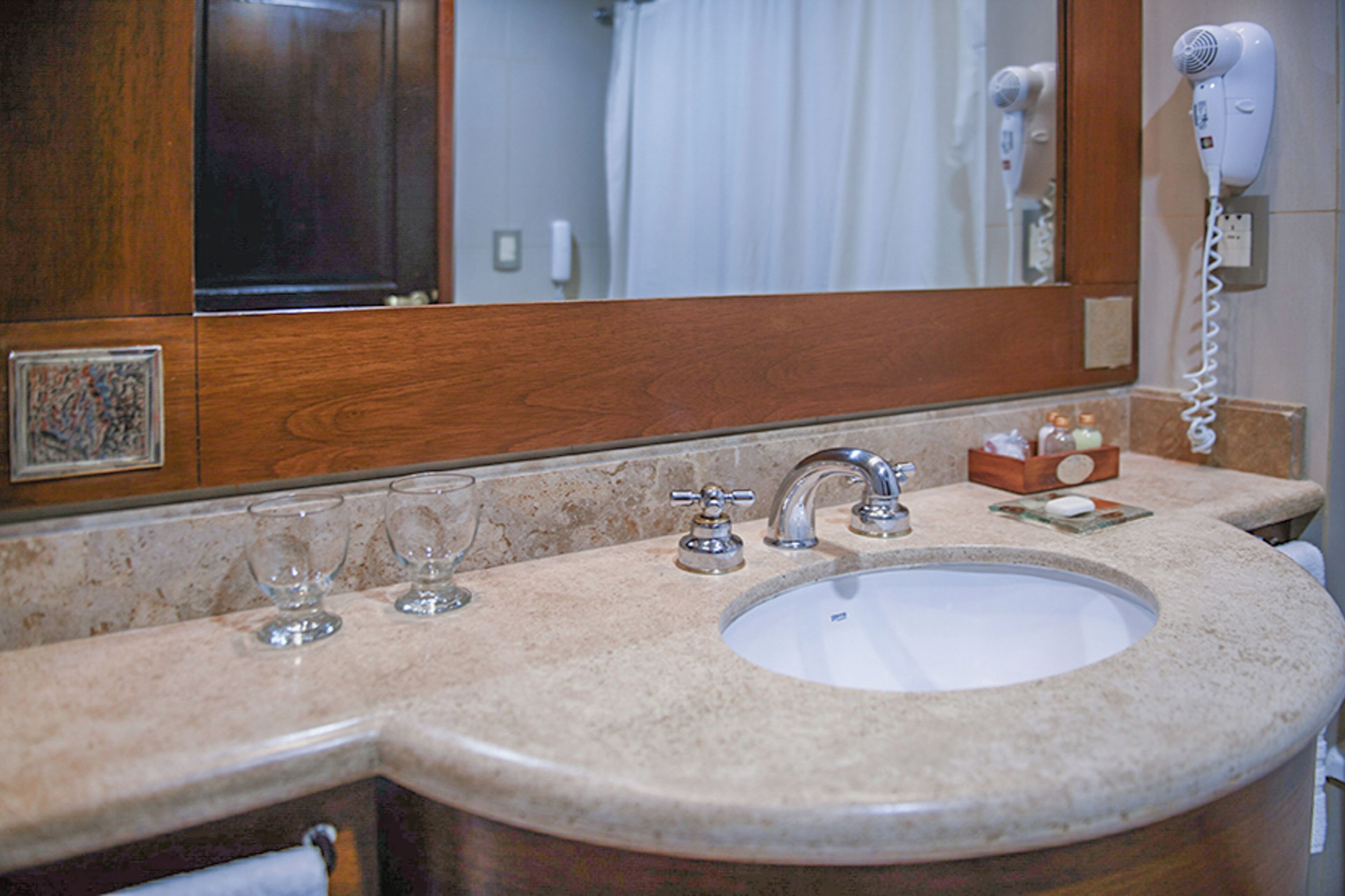 A bathroom with a sink, mirror, and hair dryer.