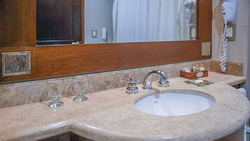 A bathroom with a sink, mirror, and hair dryer.