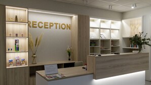 A reception area with a wooden reception desk, a reception sign, and shelves with brochures and decorative items. - Art Hotel William (Bratislava)
