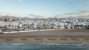 Un complejo turístico frente al mar con varios edificios de hotel, una playa de arena y vistas al océano.