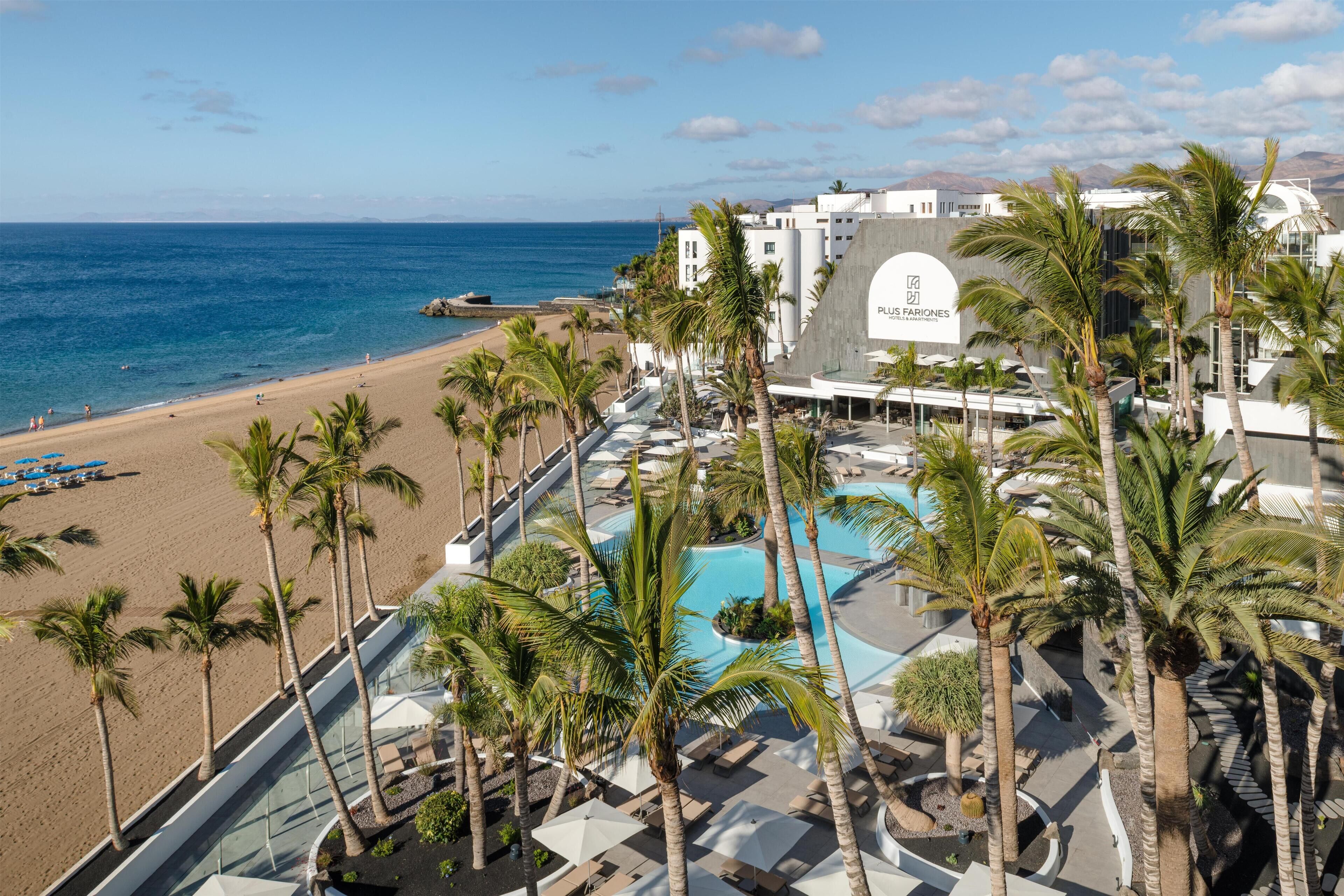 A resort with a pool, palm trees, and a beach.
