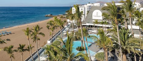 A resort with a pool, palm trees, and a beach.