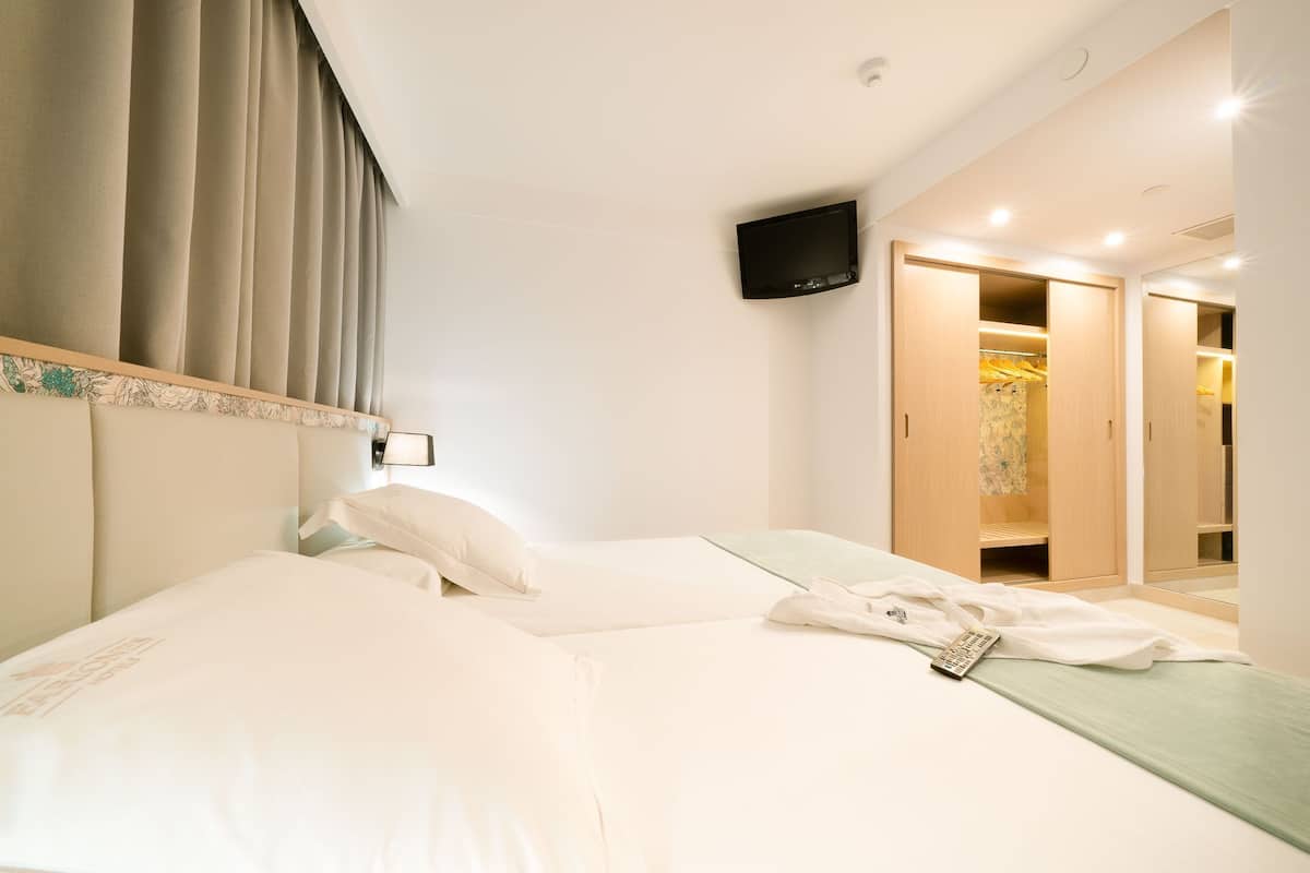 Een hotelkamer met een bed, een aan de muur bevestigde televisie en een inloopkast.
