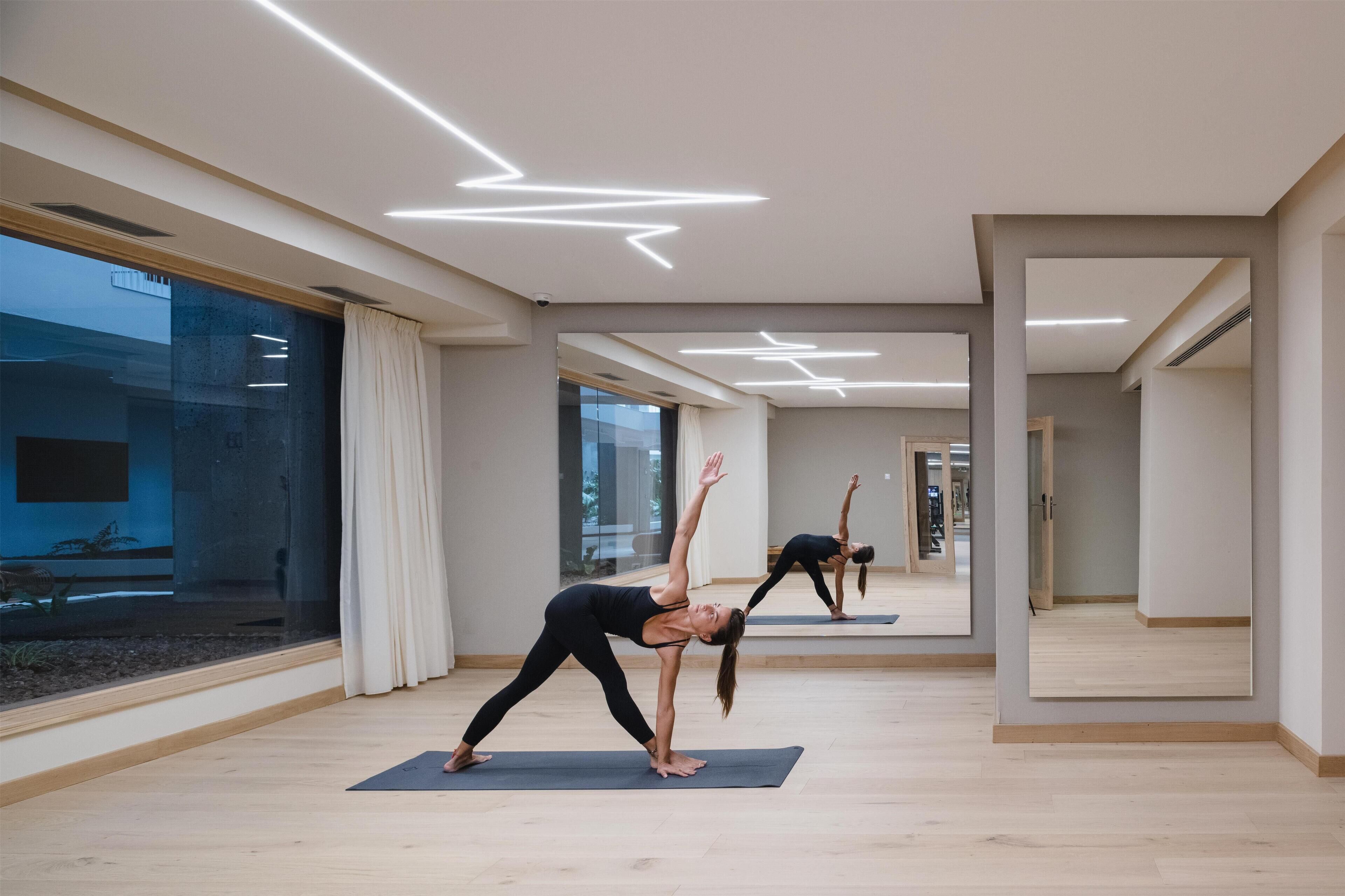 A modern yoga studio with wooden floors, large windows, and a minimalist design.