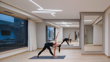 A modern yoga studio with wooden floors, large windows, and a minimalist design.