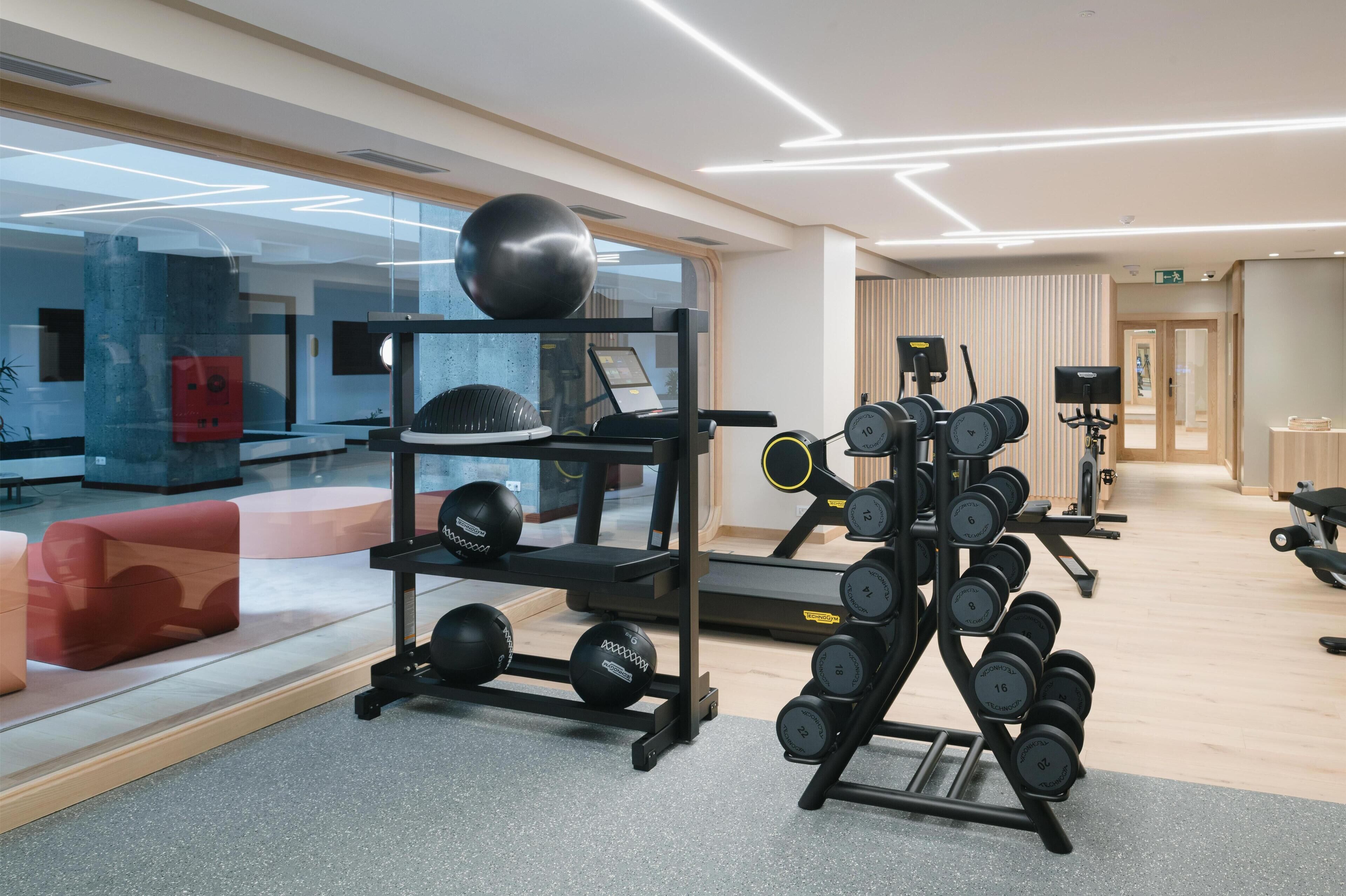 Un gimnasio moderno con equipo de ejercicio, una cinta de correr y un espejo grande.