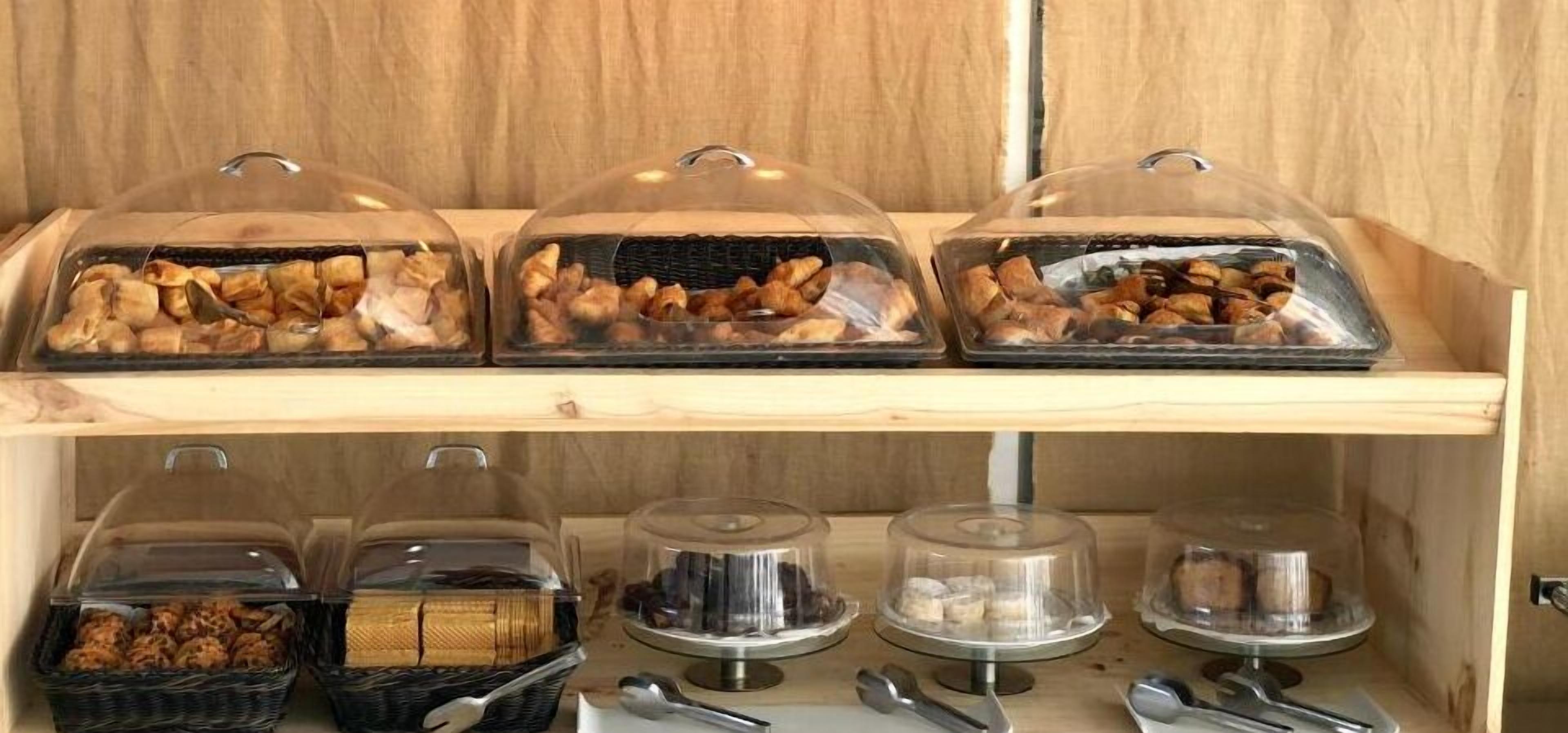 Una presentación de alimentos con varios recipientes tapados sobre una estante de madera.