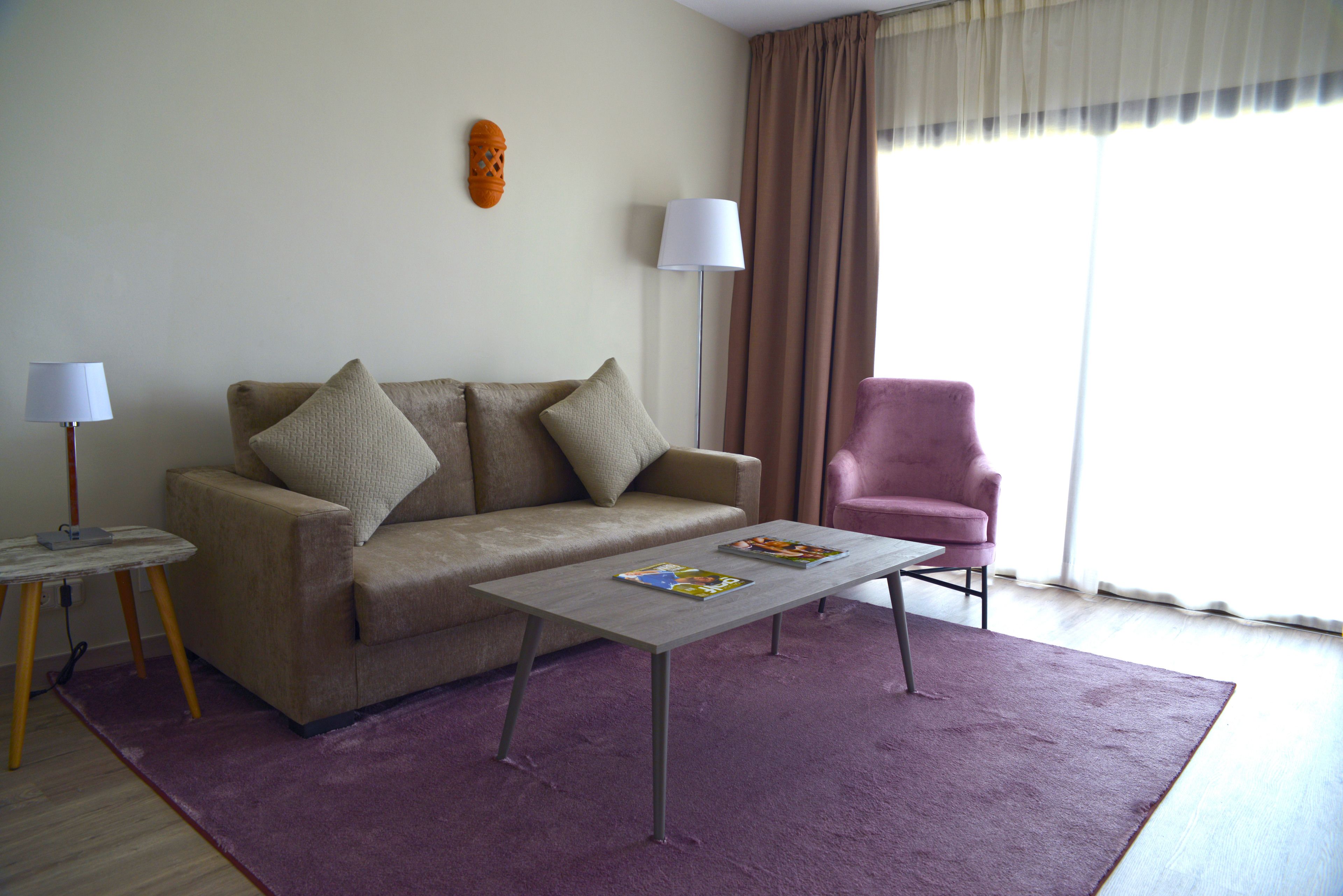 A living room with a sofa, a coffee table, a lamp, and a chair.