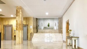 A spacious lobby with marble flooring, a central staircase, and a reception desk. - Hotel TRH Paraiso (Estepona)