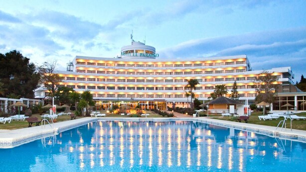 A hotel with a large pool, multiple floors, and a well-lit facade. - Hotel TRH Paraiso (Estepona)