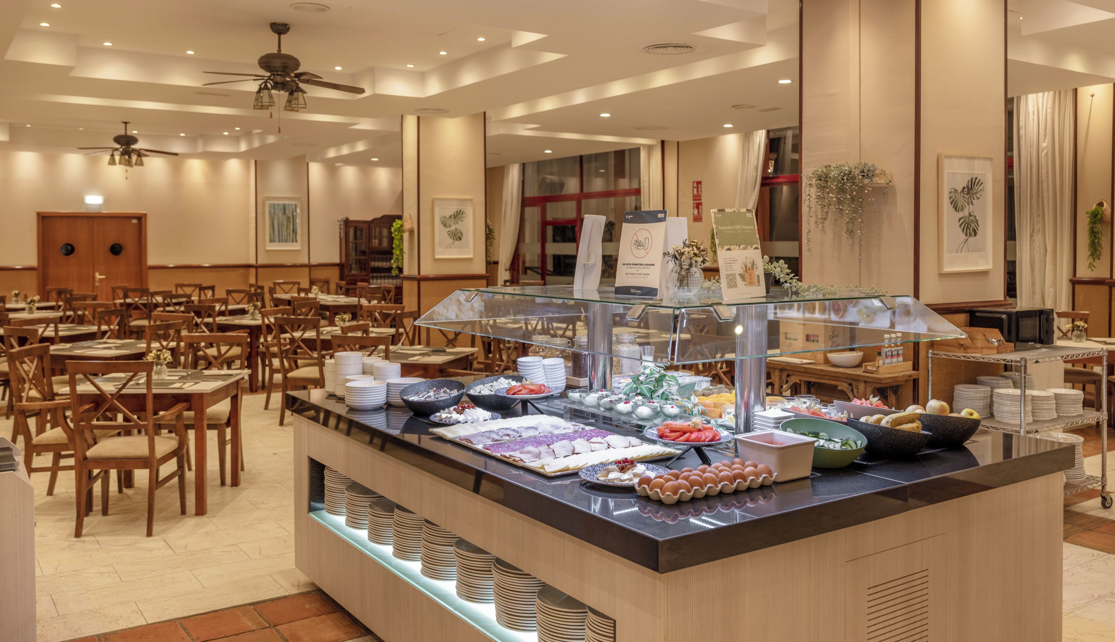A buffet area with a variety of food items, a glass display case, and multiple seating tables with chairs.