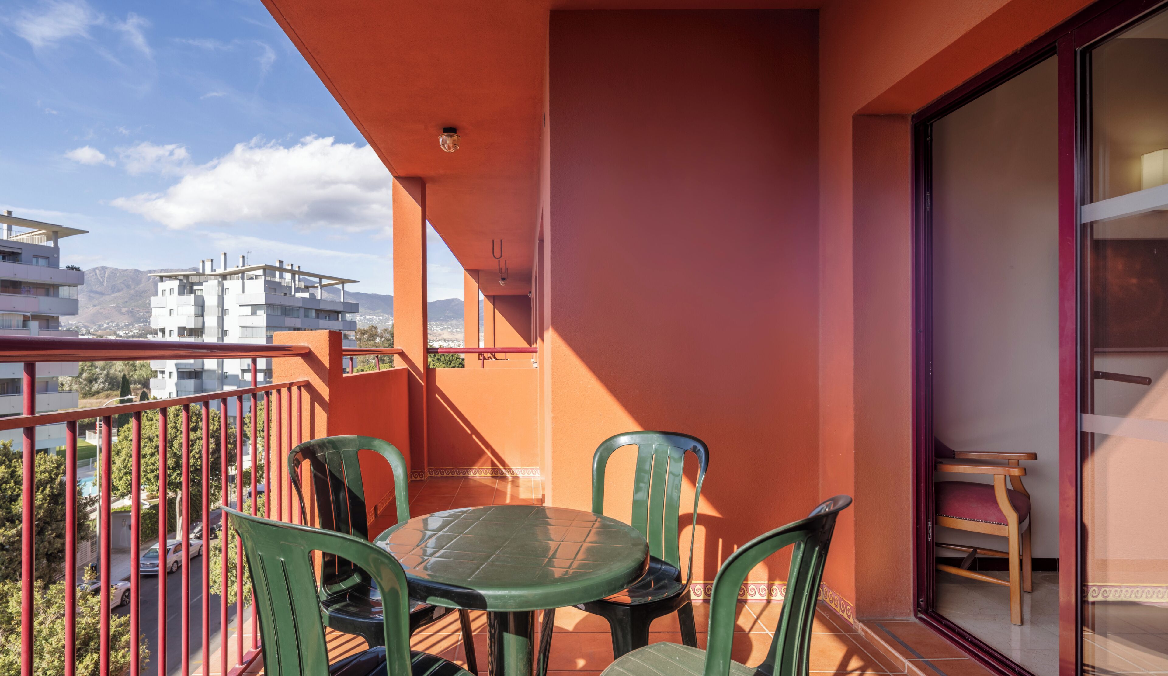 A balcony with a table and chairs, a view of buildings, and a door.