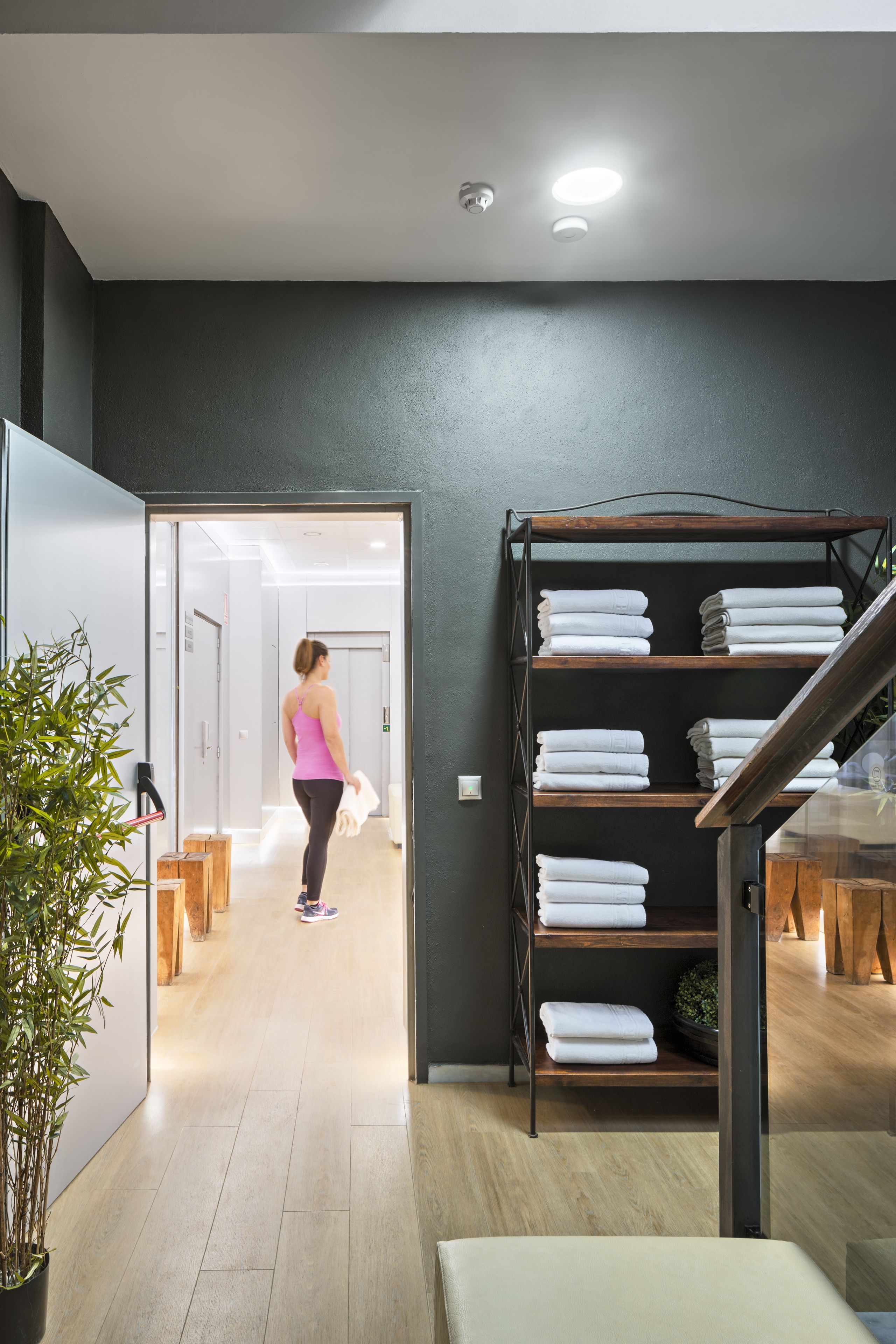 A modern interior with a staircase, a wooden bench, and a shelf with folded towels.