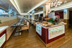 A restaurant with a long counter, multiple tables, and a buffet area with bread and plates. - Bluesea Alboran (Torremolinos)