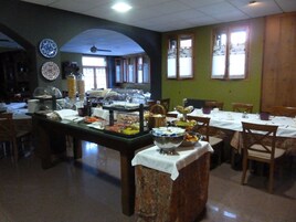 Una barra de buffet con diversos alimentos y un área de comedor con mesas y sillas.