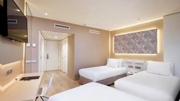 A hotel room with two beds, a desk, and a TV.