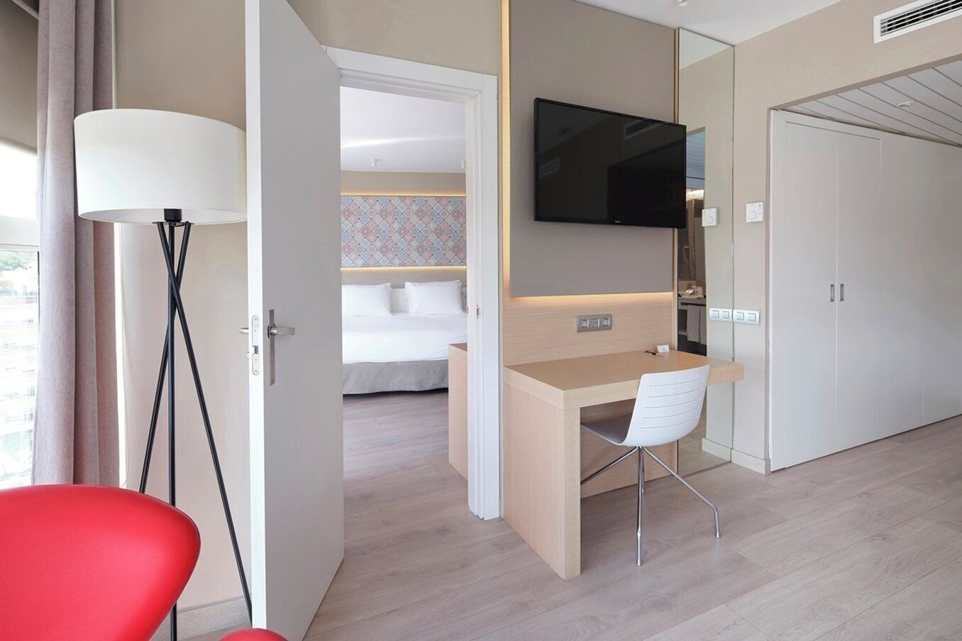 Ein Hotelzimmer mit Bett, Schreibtisch, Stuhl, Fernseher und Kleiderschrank.