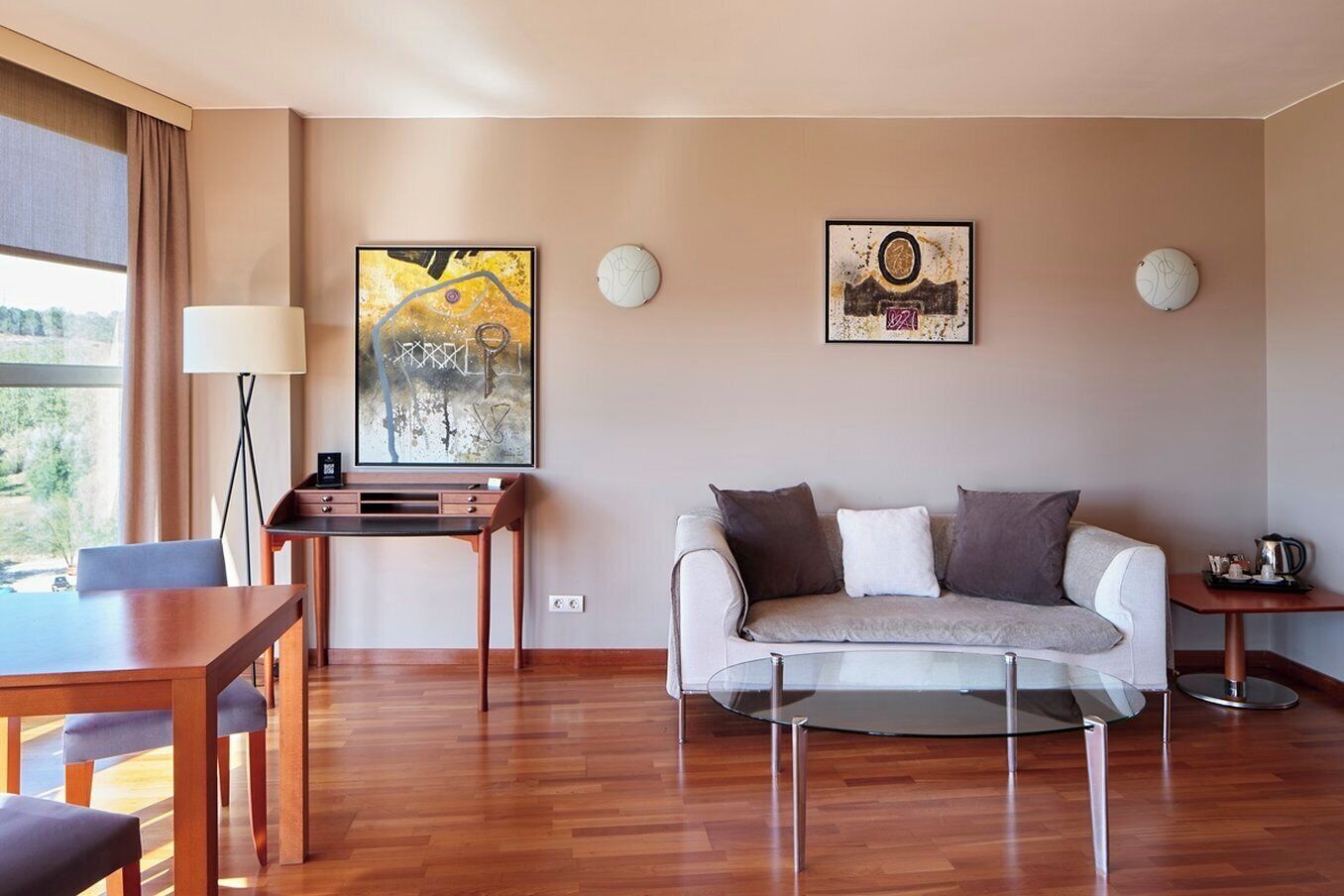 Una sala moderna con un sofá, una mesa de centro, un escritorio y dos relojes de pared.
