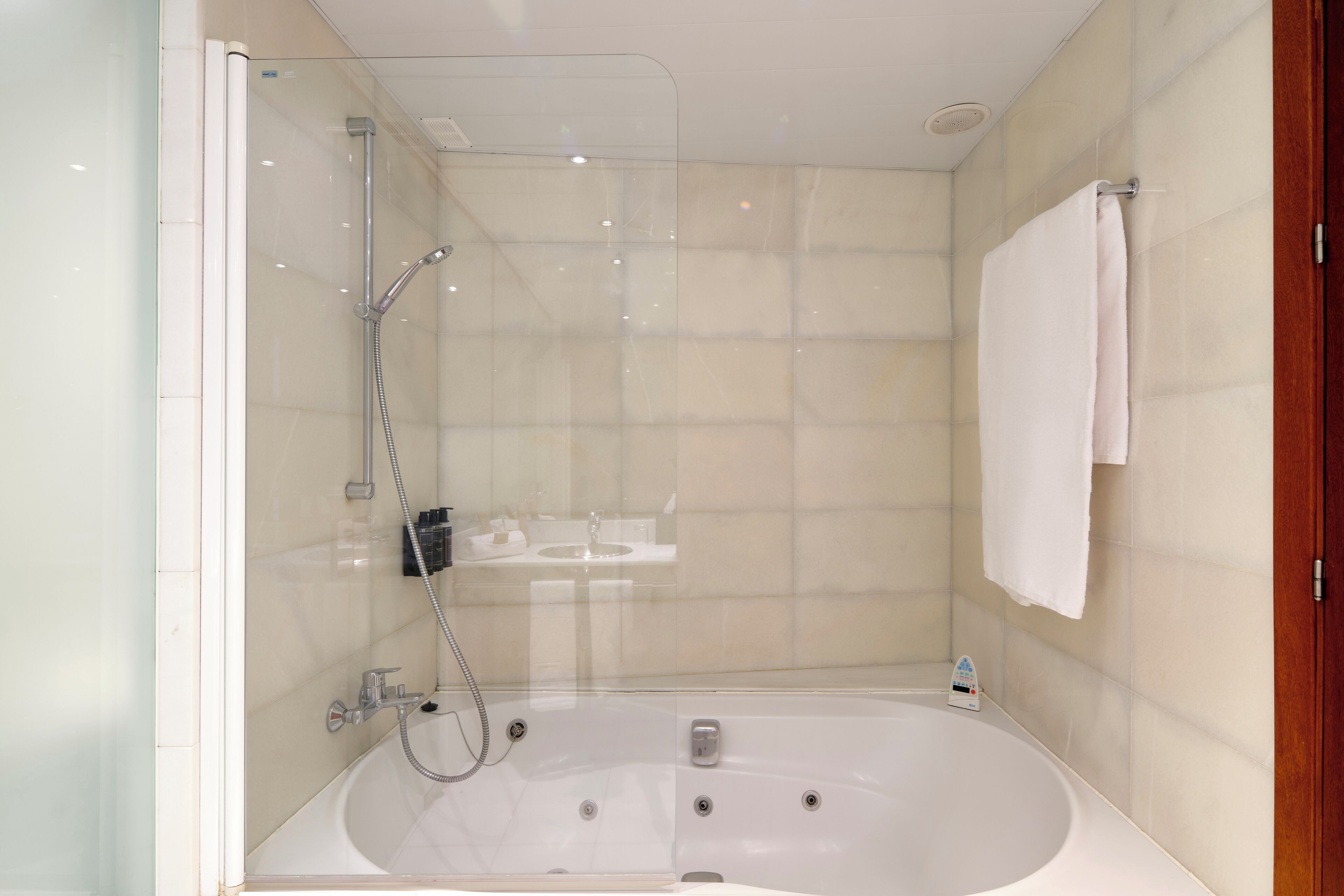 Un baño moderno con ducha de vidrio, una bañera independiente y una toalla blanca colgada en la pared.