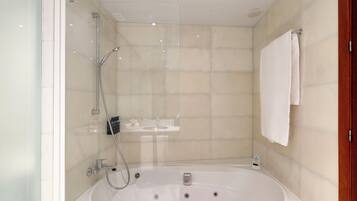 Un baño moderno con ducha de vidrio, una bañera independiente y una toalla blanca colgada en la pared.