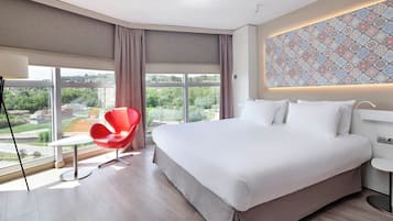 Een moderne hotelkamer met een groot bed, een rode stoel en uitzicht op de omgeving.
