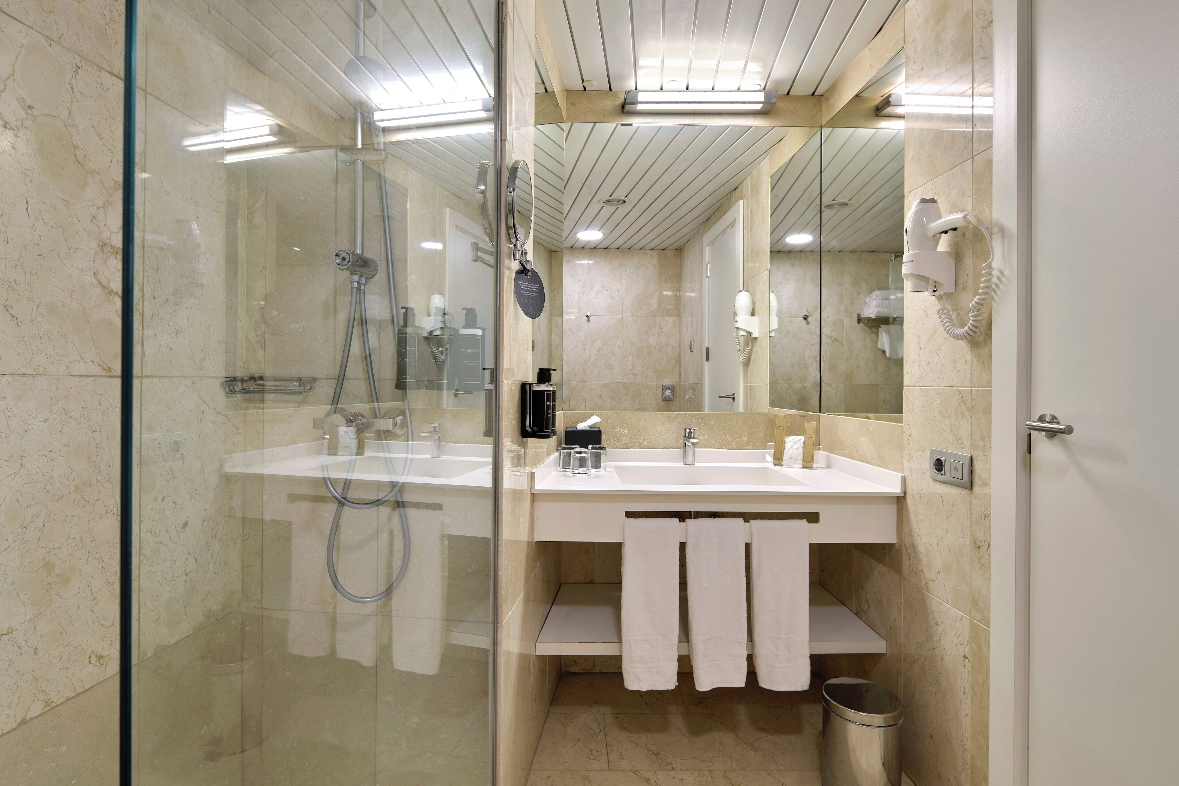 A modern bathroom with a glass-enclosed shower, a white sink, and a mirror.