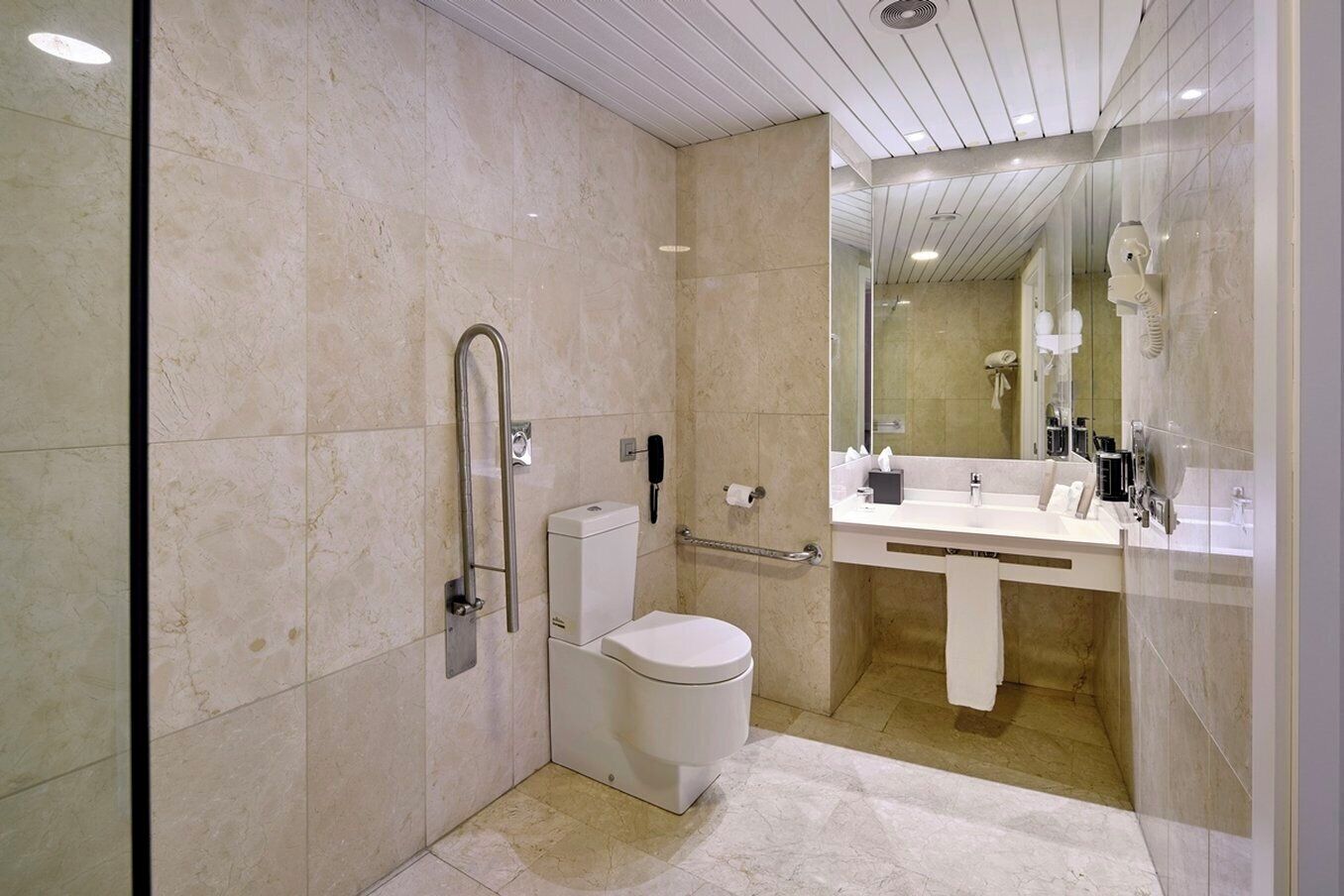 Une salle de bain moderne équipée de toilettes, d’un bidet et d’une douche séparée par une paroi en verre.