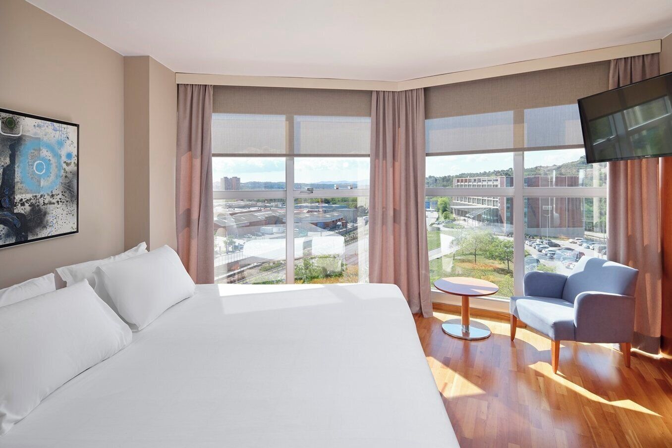 A hotel room with a large bed, a small round table, a sofa, and a TV.